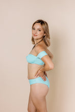 Load image into Gallery viewer, Girl in blue bikini set. Bandeaux Top has off-shoulder sleeves. Side shot
