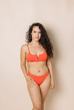 Load image into Gallery viewer, Girl in coral bikini set. scoop front bottoms with ruching in the back. Front shot
