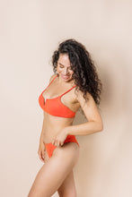 Load image into Gallery viewer, Girl in coral bikini set. scoop front bottoms with ruching in the back. Side shot
