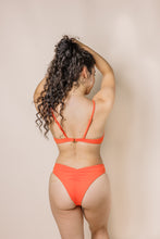 Load image into Gallery viewer, Girl in coral bikini set. scoop front bottoms with ruching in the back. Back shot
