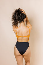 Load image into Gallery viewer, Girl in colour block one piece bikini with cut out. Top is burnt orange and bottom is black. Back shot
