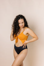 Load image into Gallery viewer, Girl in colour block one piece bikini with cut out. Top is burnt orange and bottom is black. Front shot
