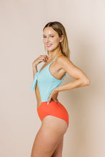 Load image into Gallery viewer, Girl in colour block one piece bikini with cut out. Top is blue and bottom is coral. Side shot
