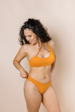 Load image into Gallery viewer, Girl in burnt orange bikini set. scoop front bottoms with ruching in the back. Front shot

